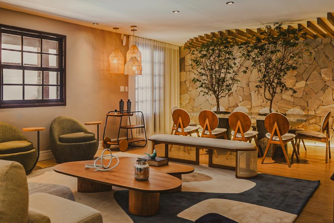 Ambientes de estar e jantar integrados com tapete geométrico, móveis de madeira, cortinas e vegetação